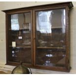 An early 20th century oak stained hanging wall cabinet with shaped cornice, twin glazed doors with