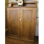 A Victorian pine side cabinet with shaped top, two panelled doors enclosing a shelved interior on