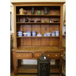 An old pine dresser with shaped cornice, fluted supports, three adjustable shelves with three frieze