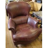 A Victorian mahogany framed serpentine fronted red leather upholstered library chair with carved arm