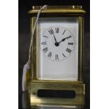 A vintage brass carriage clock with handle, Roman numerals on a shaped base
