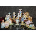 An assortment of thirteen Beatrix Potter ceramic figurines, some on a stylized base