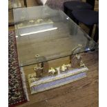 A contemporary oblong glass topped coffee table raised on four bronzed lions and faux marble