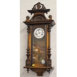 A Viennese wall clock, enameled dial with Roman numerals, carved cornice and two lower turned