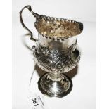 A Victorian silver cream jug on single foot decorated in relief, London 1891