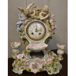 A European porcelain elaborately carved and decorated mantle clock surmounted by a pair of