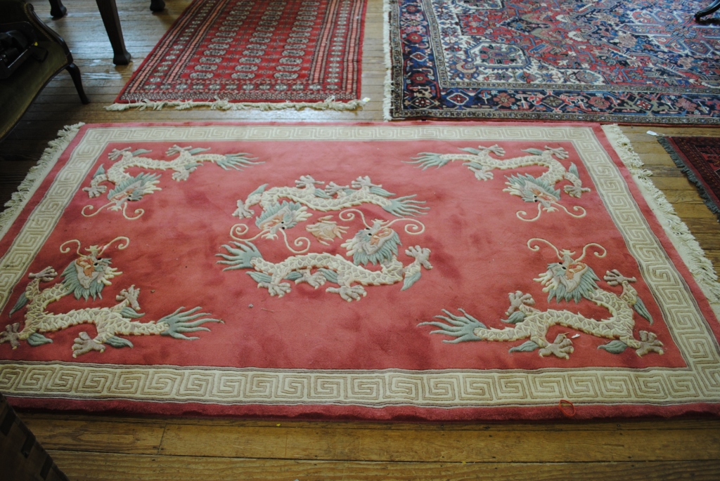 A pink-ground 'Jade' super washed Chinese wool rug depicting five dragons with Greek-key border
