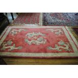 A pink-ground 'Jade' super washed Chinese wool rug depicting five dragons with Greek-key border