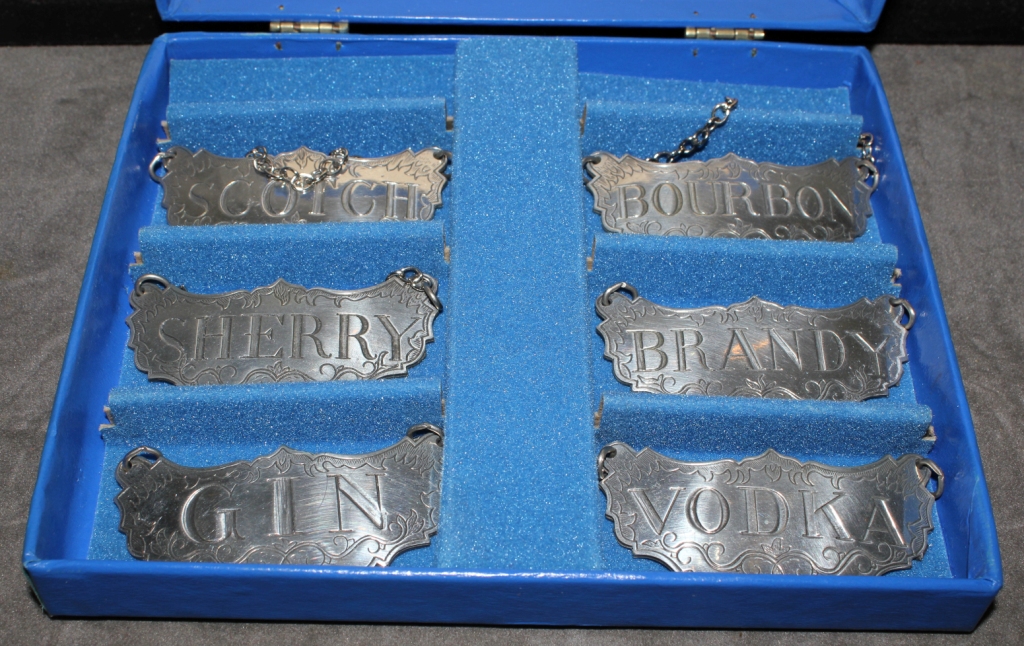 A box set of six Stieff pewter decanter labels, scotch, bourbon, sherry, brandy, gin and vodka