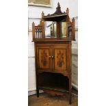 An Edwardian corner cabinet, twin inset mirror, carving to doors, brass rods, cornice with