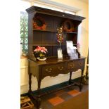 A large stained oak dresser with two drawers, each with a pair of brass drop handles on turned