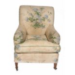 A FLORALLY UPHOLSTERED HOWARD STYLE ARMCHAIR standing on square section legs and ceramic castors