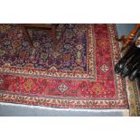 A TABRIZ RED AND BLUEGROUND CARPET with symmetrical floral patterns and multiple banded border,