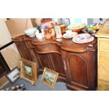 A VICTORIAN MAHOGANY SERPENTINE FRONTED SIDEBOARD with central frieze drawer above four panelled