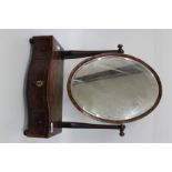 A 19TH CENTURY MAHOGANY SERPENTINE FRONTED DRESSING TABLE MIRROR, the oval mirror frame on shaped