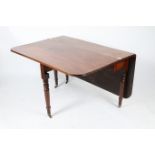 A 19TH CENTURY MAHOGANY DROP LEAF DINING TABLE standing on turned legs terminating in brass feet and