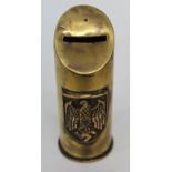 A BRASS MONEY BOX made from a World War II shell casing and applied with a Nazi emblem, the casing