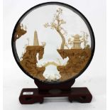 AN ORIENTAL CORK AND PAPER DIORAMA in the circular frame with temples in a landscape and scrolling