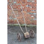 AN OLD WOODEN CAST IRON SEED DRILL with label for Horace Fuller Ltd, Horsham, 59cm wide