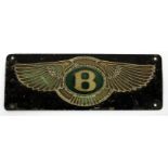 A BLACK PAINTED AND GREEN ENAMEL DECORATED BENTLEY FIREWALL EMBLEM FROM A 1930'S BENTLEY MOTOR CAR