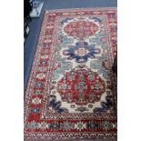 AN ORIENTAL CREAM GROUND RUG with three geometric designs to the centre within a triple banded