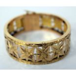 AN 18 CARAT GOLD HINGED BANGLE, flowerhead design, clasp stamped 18K