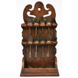 AN OLD OAK SPOON RACK WITH PIERCED SCROLLING DECORATION and a collection of pewter spoons and forks.