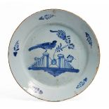 A GEORGE III BRISTOL DELFTWARE PLATE decorated with a bird perched on a fence, 21.8cm diameter (