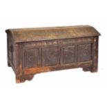 AN ANTIQUE OAK COFFER with domed top and quadruple panelled front with chip carved decoration,