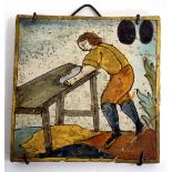 A 17TH CENTURY TIN GLAZED TILE depicting a workman at his bench, 13.4cm square (restorations)