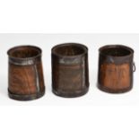 A GROUP OF THREE 18TH CENTURY OAK OR ELM IRON BOUND TAPERING CYLINDRICAL VESSELS with chip carved