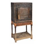 A 17TH CENTURY STYLE OAK CUPBOARD with chip carved decoration to the front, the panel door bearing