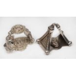 TWO EARLY 20TH CENTURY IRISH BRITANNIA SILVER NAPKIN RINGS in the form of illuminations from the