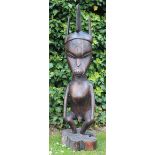 A LARGE CARVED WOODEN FIGURE OF A MAN WITH HEADDRESS, star motif and naturalistic base, signed '