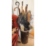 A CYLINDRICAL OAK STICK STAND together with a quantity of various Victorian and later umbrellas,