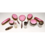 A SILVER AND PINK ENAMEL BACKED PART DRESSING TABLE SET consisting of four brushes, a hand mirror,