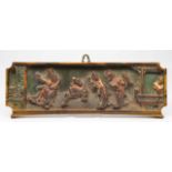 AN ANTIQUE CHINESE PAINTED CARVED WOODEN PANEL of four figures on a grassy hill, 34.8cm x 14cm