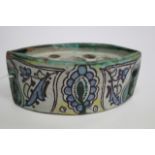 A SMALL NAVETTE SHAPED IZNIK STYLE TIN GLAZED POTTERY INKWELL with stylised floral decoration,