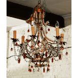 A DECORATIVE WROUGHT IRON SIX BRANCH ELECTROLIER decorated with cut glass drops, amber glass