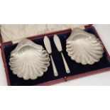 A PAIR OF SILVER SHELL SHAPED BUTTER DISHES each standing on three ball feet together with a pair of