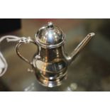 AN ANTIQUE WHITE METAL COFFEE POT of baluster form and with scroll handle on a circular spreading