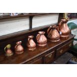 A MATCHED SET OF FIVE GRADUATED VICTORIAN COPPER MEASURES ranging from 2 gallons to a pint, the