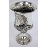 A VICTORIAN SILVER TROPHY CUP with embossed floral swag and laurel wreath decoration, standing on
