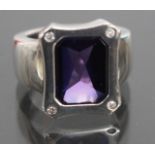 A DECORATIVE SILVER RING set with a rectangular purple stone by 'Follie'