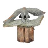 AN AFRICAN CARVED GREEN HARDSTONE SCULPTURE in the form of an eagle on a log, on a naturalistic