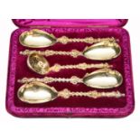 A CASED SET OF VICTORIAN SILVER GILT SERVING SPOONS AND A SUGAR SIFTER, each with figural finials