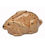 A SMALL GLAZED POTTERY MONEY BOX in the form of a crouching rabbit, 12cm long