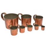 A SET OF EIGHT GRADUATED COPPER RUM MEASURES each with a looping handle, the largest 1 gallon and