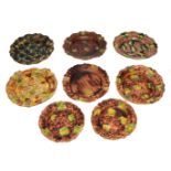 A GROUP OF EIGHT WHEILDON TYPE GLAZED POTTERY PLATES each with varying decoration and shaped edge,