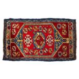 AN ANATOLIAN WOOLLEN YASTIK with a hooked design on a deep red ground, 19th Century, 100cm x 54cm